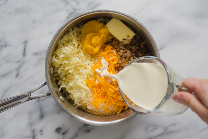 Pouring the cream into the pot with the rest of the ingredients.