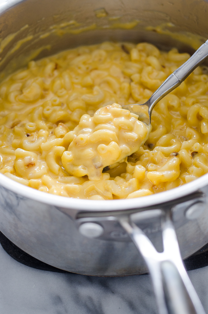 A spoonful of butternut squash mac and cheese held over the pot.