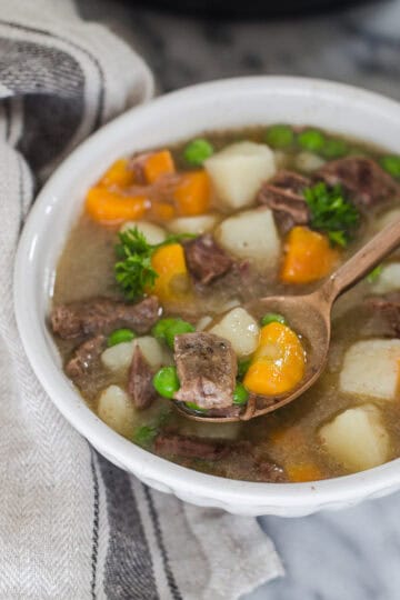 A bowl of Instant Pot Beef Stew with a napkin off to the side and a spoon.