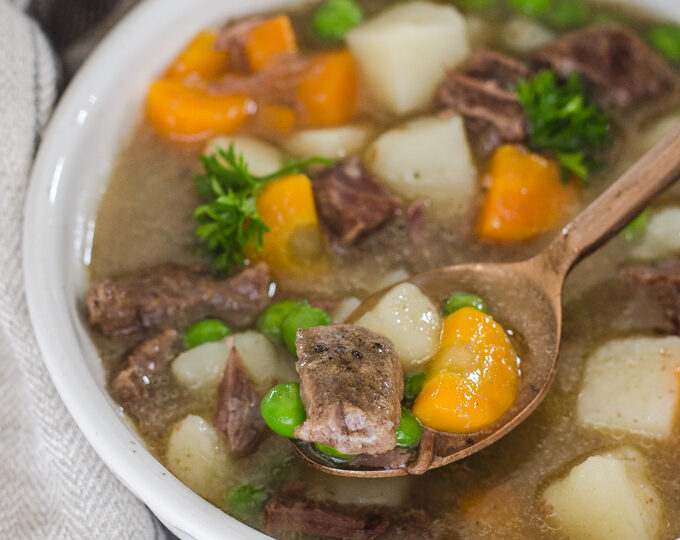 A bowl of Instant Pot Beef Stew with a napkin off to the side and a spoon.