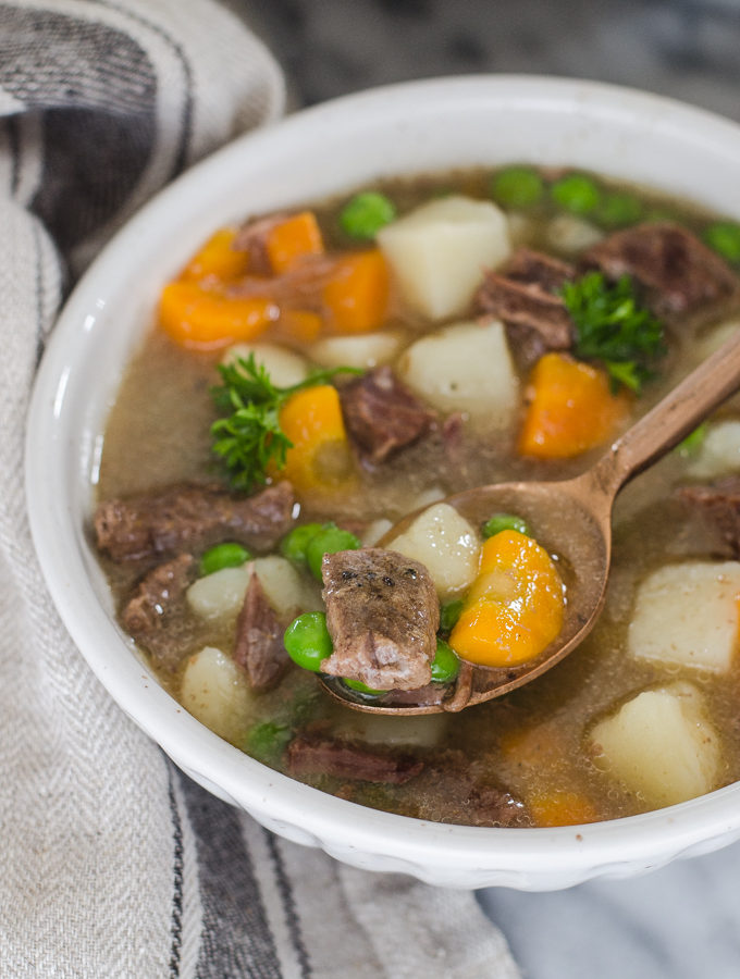 A bowl of Instant Pot Beef Stew with a napkin off to the side and a spoon.