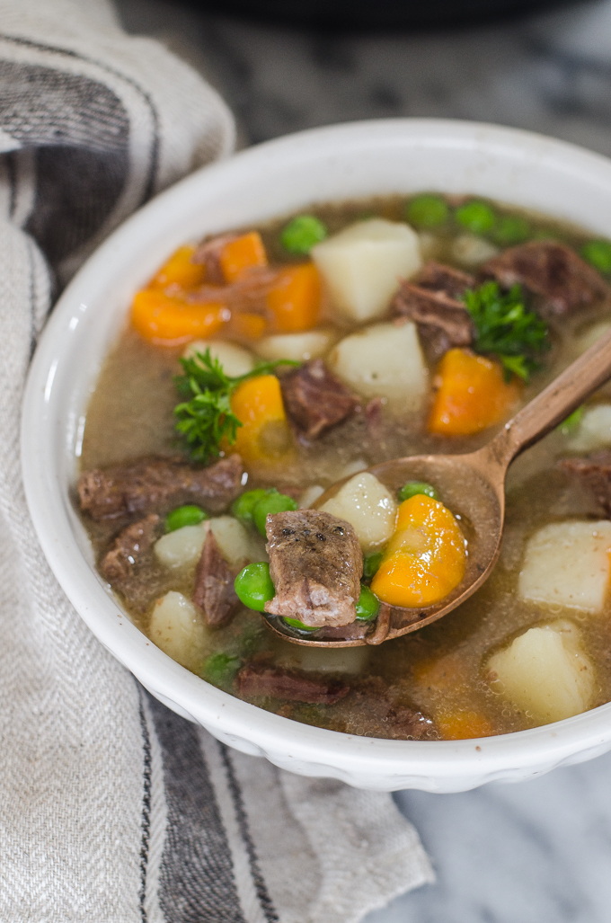 A bowl of Instant Pot Beef Stew with a napkin off to the side and a spoon.