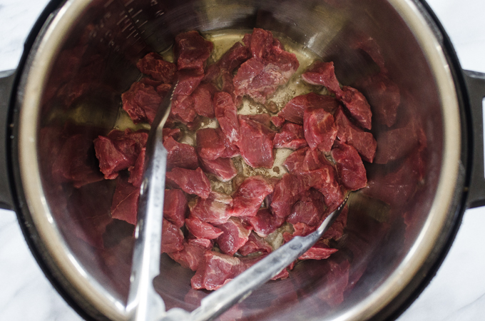 Adding the beef to the hot instant pot.