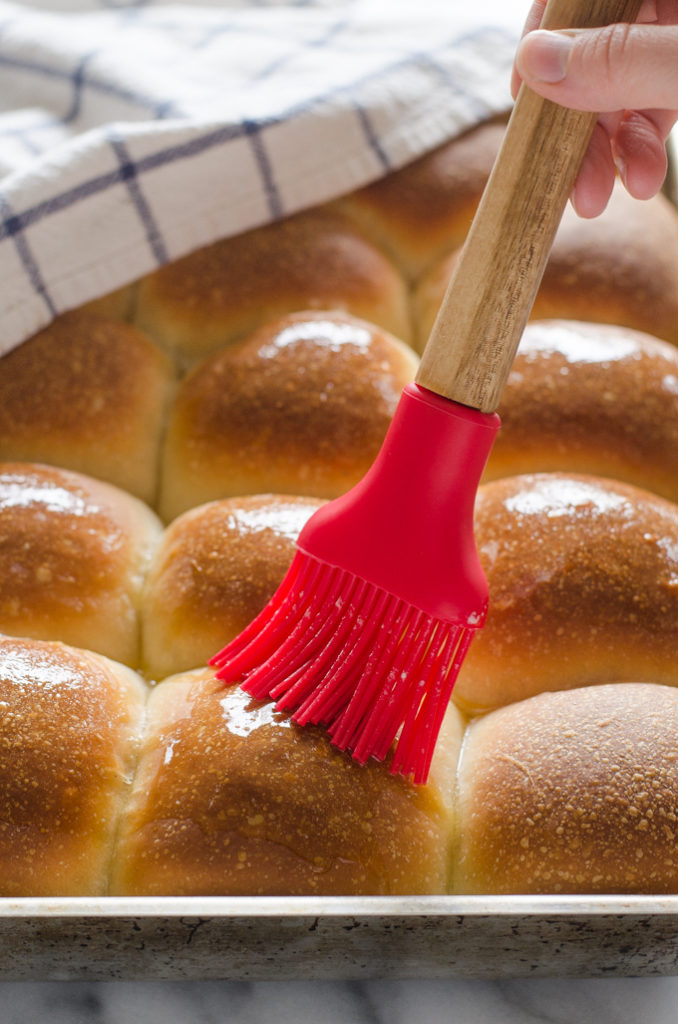 Brushing Sourdough Pull Apart Rolls with melted butter.