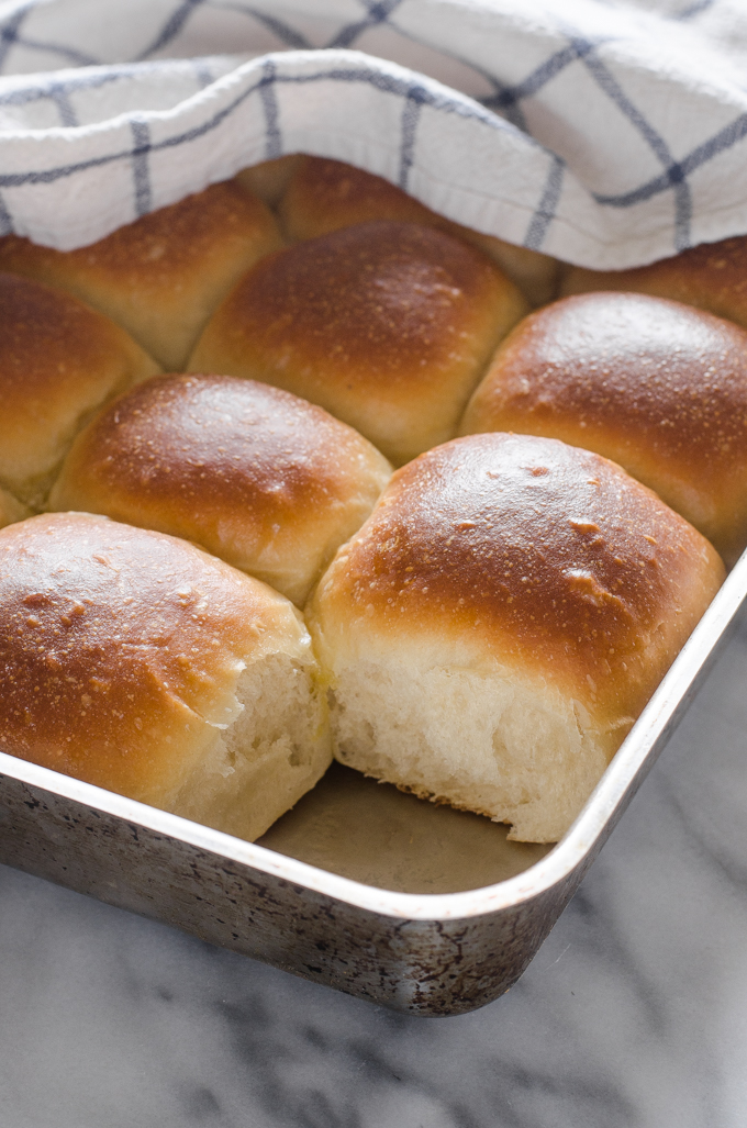 Pan of sourdough pull apart rolls with one taken out of the pan.