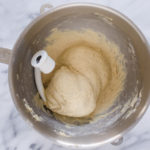 The dough all kneaded in the bowl of a stand mixer.