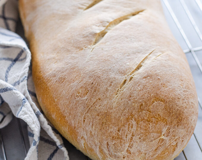 A loaf of Soft Sourdough French Bread No Yeast all baked and on a cooling rack.