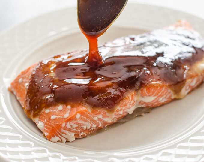 Drizzling homemade teriyaki sauce on a fillet of salmon.