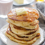 A stack of sourdough pancakes with a pat of butter and maple syrup dripping off the sides.