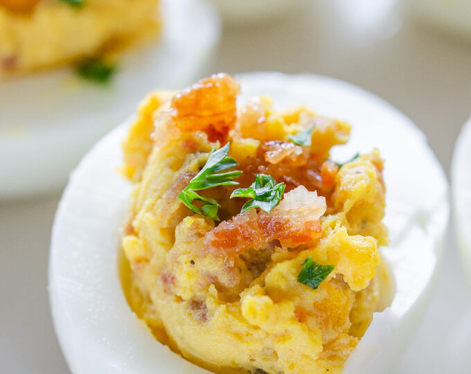 Close up shot of deviled eggs with bacon and parsley.