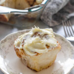 A sourdough cinnamon roll with cream cheese icing on a small plate.