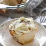 A sourdough cinnamon roll with cream cheese icing on a small plate.