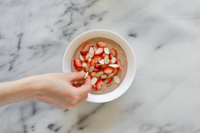 Adding the strawberries and almonds to the chocolate yogurt.