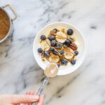 Drizzling almond butter over the yogurt, bananas, blueberries, and granola.