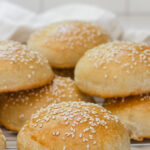 Sourdough hamburger buns on a cooling rack.