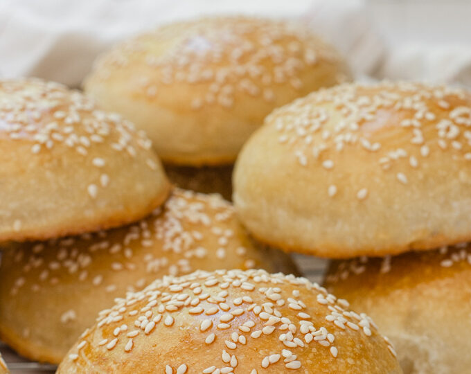 Sourdough hamburger buns on a cooling rack.