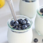 Jars of yogurt panna cotta with blueberries in them.