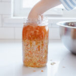 Packing spicy sauerkraut into a wide mouth mason jar.