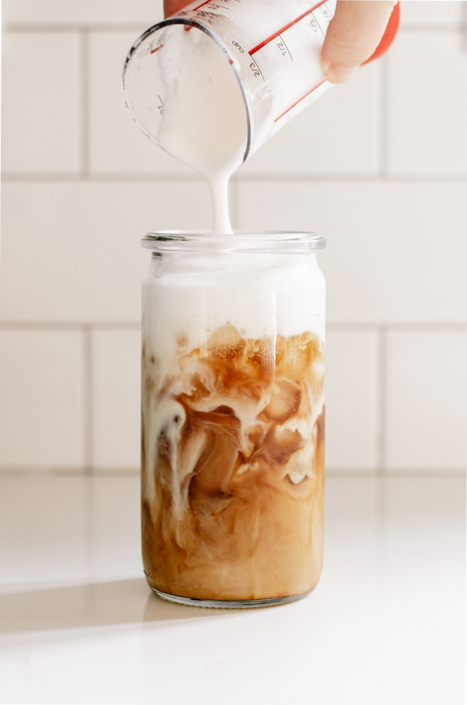 Pouring cold foam over iced coffee. 