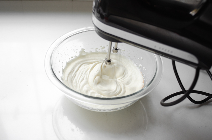 Whipping the nutmeg whipped cream until soft peaks form.