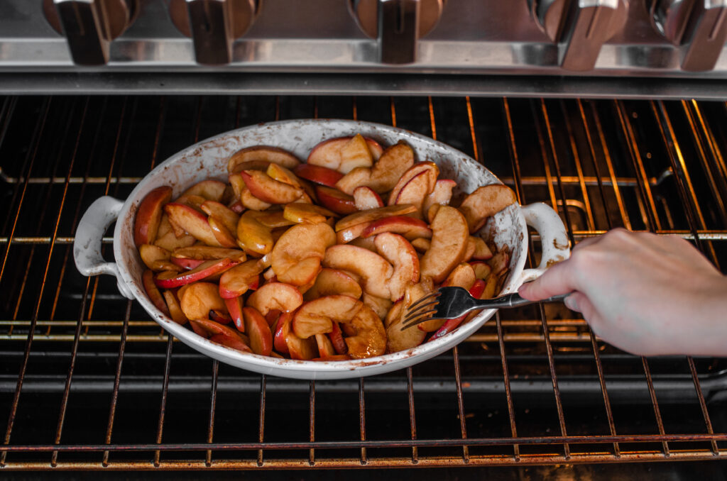 Testing the apple slices for doneness with a fork.