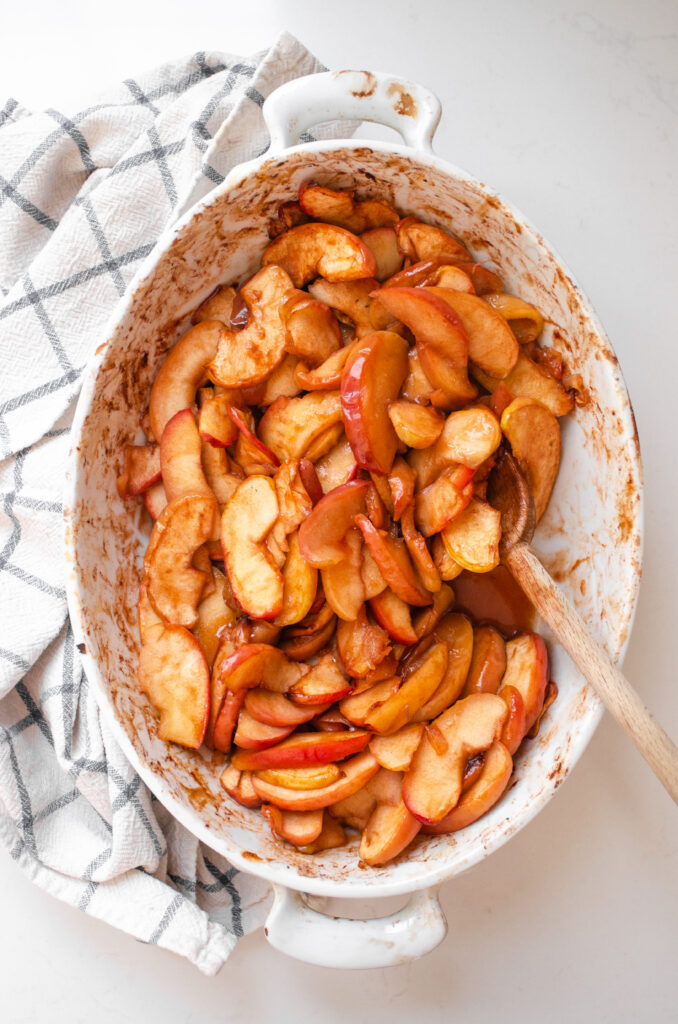 An oval baking dish of baked cinnamon apples.