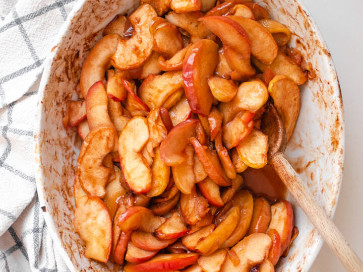 An oval baking dish of baked cinnamon apples.