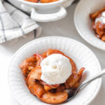 A bowl of baked cinnamon apples with a scoop of vanilla ice cream on top.