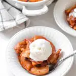 A bowl of baked cinnamon apples with a scoop of vanilla ice cream on top.