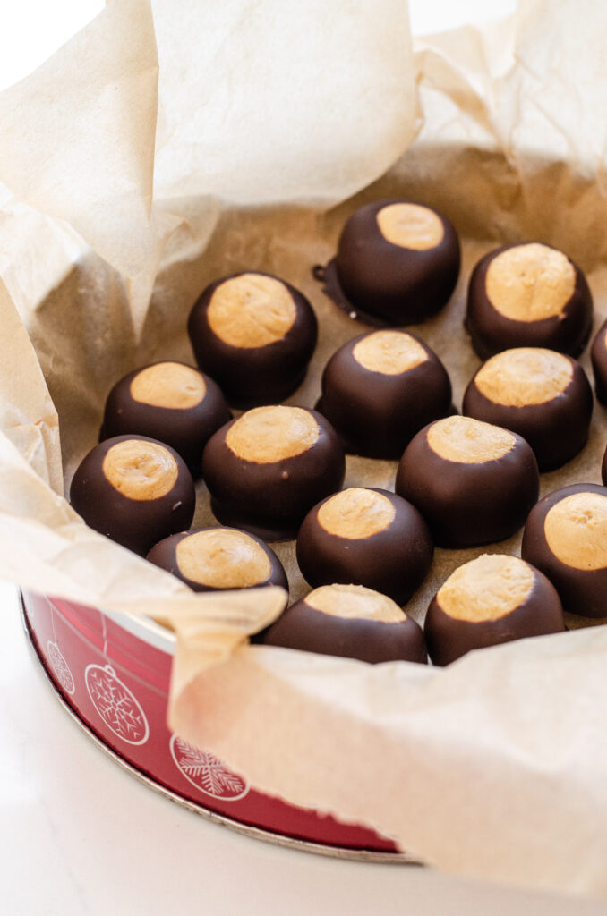 Homemade Buckeye recipe without shortening, placed in a Christmas tin. 