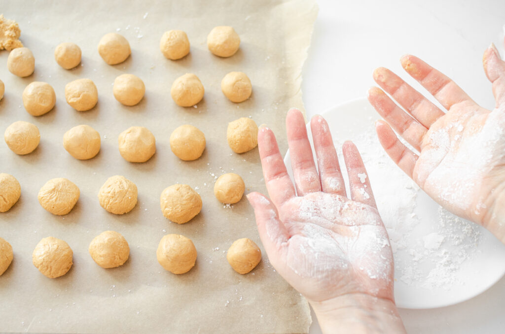 Dusting hands with powdered sugar to roll out the peanut butter balls to make buckeyes without shortening. 