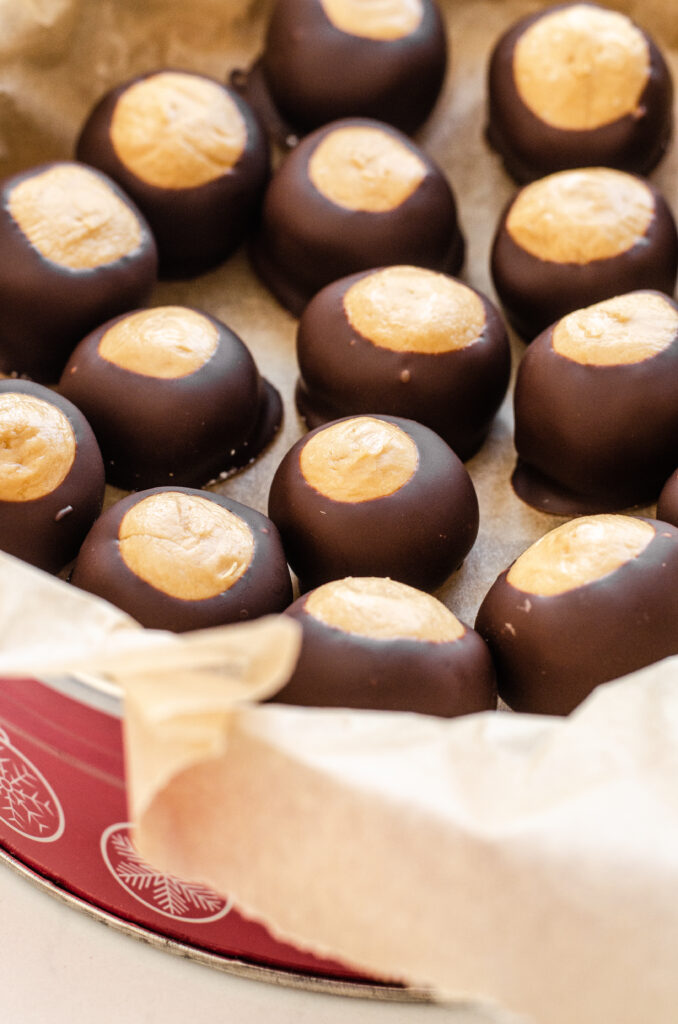 A Christmas tin full of peanut butter buckeyes made without shortening. 