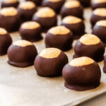 Buckeye recipe without shortening all lined up on a parchment lined baking tray.