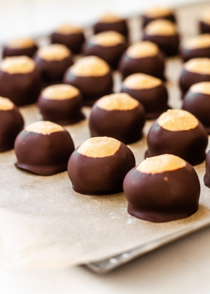 Buckeye recipe without shortening all lined up on a parchment lined baking tray.