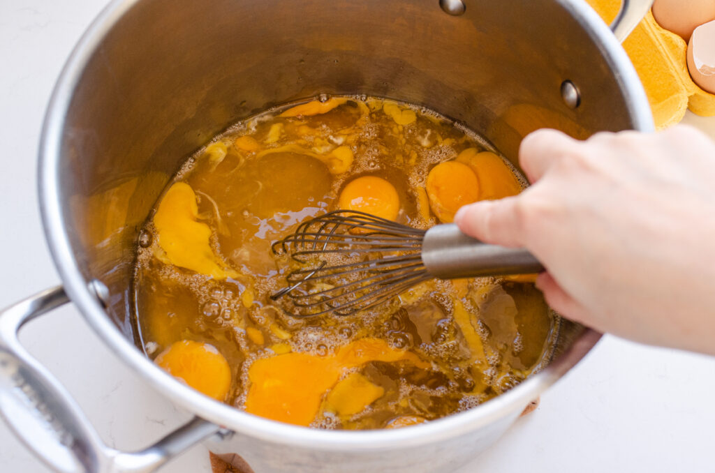 Whisking the eggs, syrup, and salt in a stock pot.
