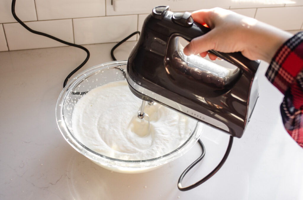 Whipping the cream until soft peaks form.