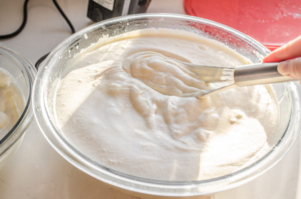 Folding the whipped cream into the custard with a wire whisk.
