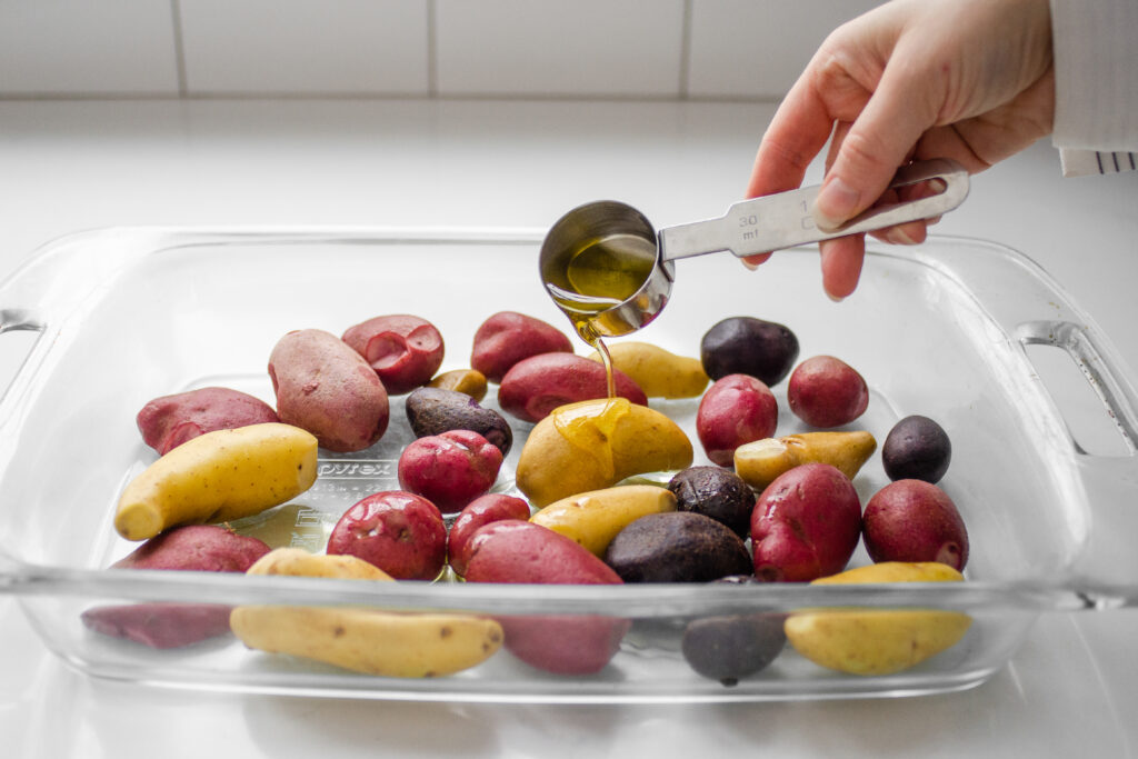 Drizzling the extra virgin olive oil over the mini potatoes. 