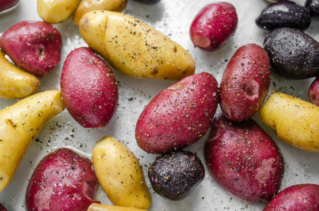 Seasoning the mini potatoes with salt and pepper in the pan.