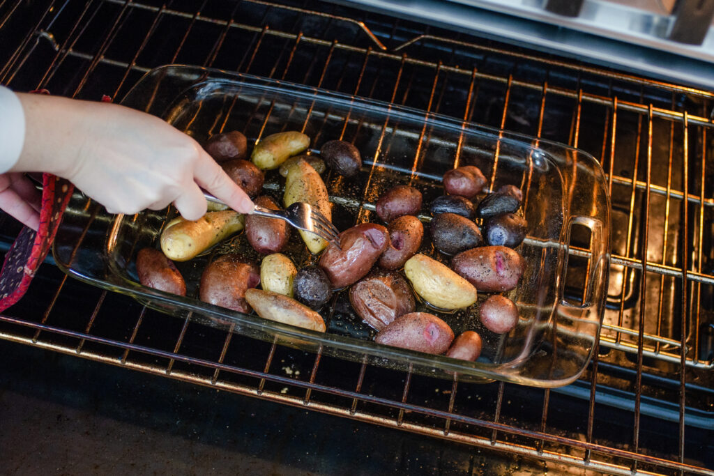 Testing the baby potatoes for doneness with a fork.