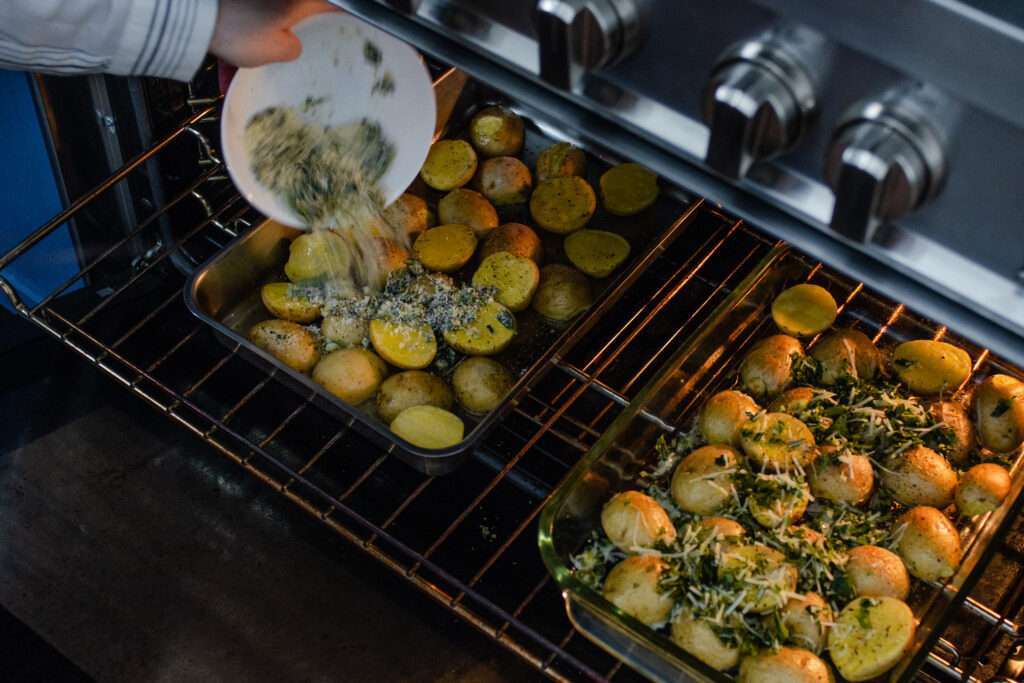 Adding the seasoning blend to the roasting little potatoes in the oven. 