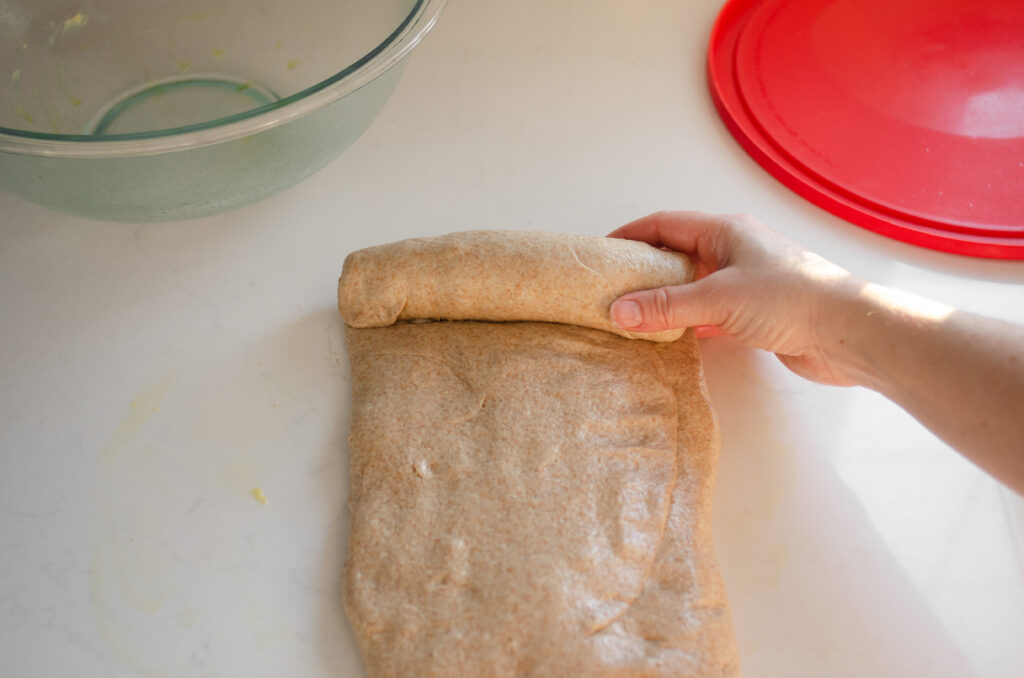 Forming the loaf of sourdough bread by rolling it up like a jellyroll. 