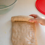 Forming the loaf of sourdough bread by rolling it up like a jellyroll.