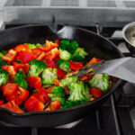 Adding the red bell peppers to the stir fry.