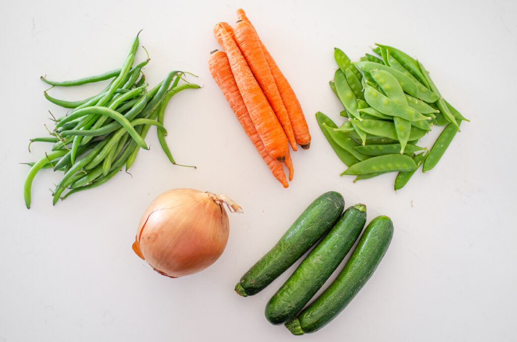Different kinds of vegetables that you can use to make a stir-fry laid out on a white counter. 