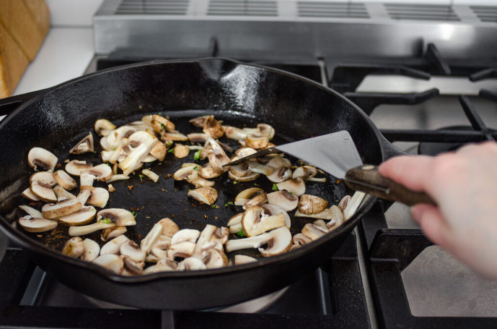 Adding the mushrooms to the pan to stir fry. 