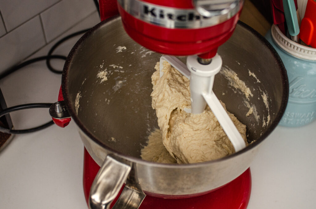 Placing the dough for the dairy free cinnamon rolls on the stand mixer base to knead. 