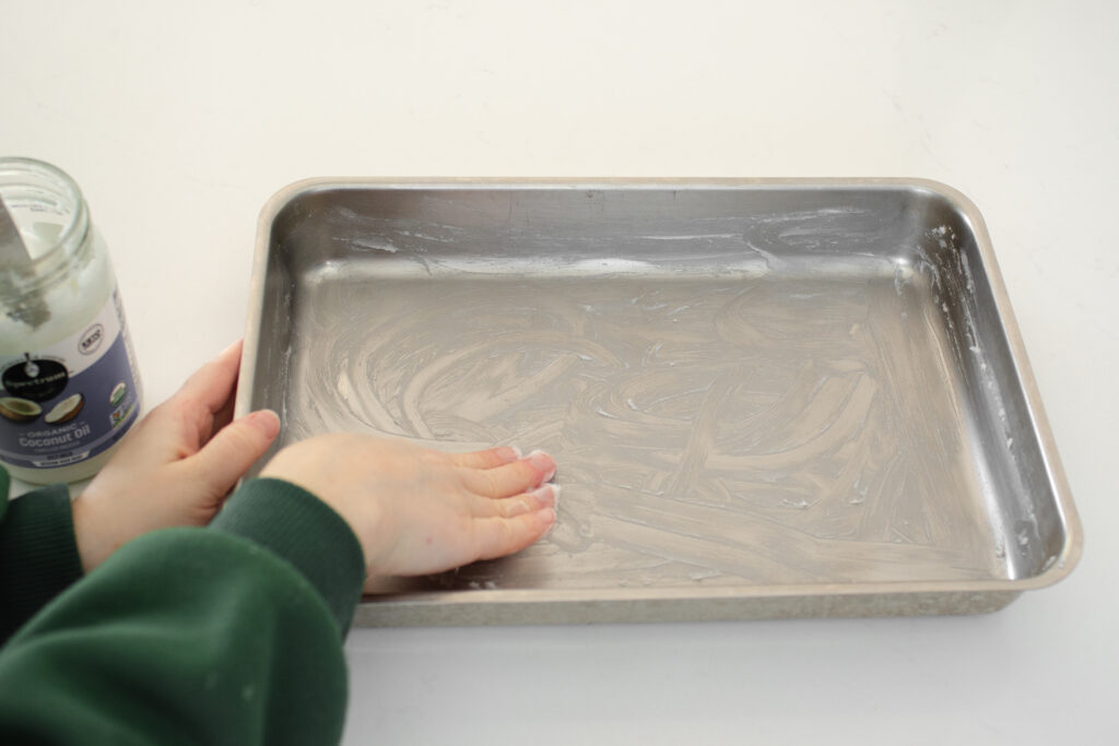 Greasing a 13x9 inch baking dish with coconut oil. 