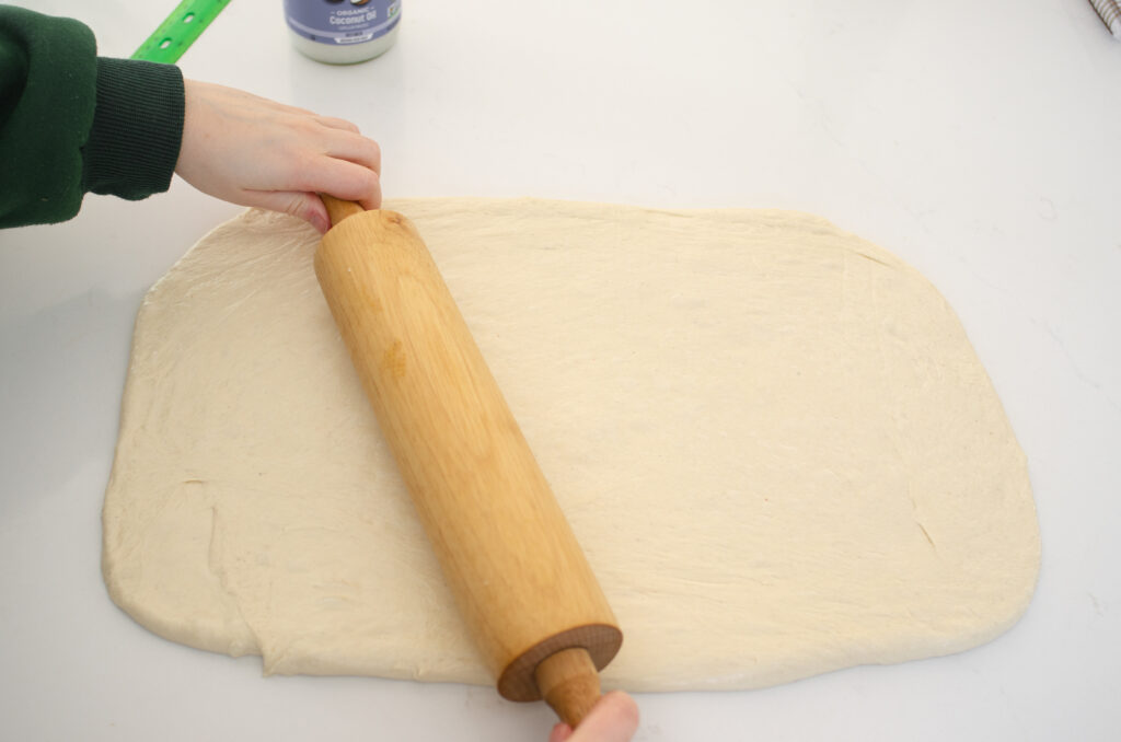 Rolling the dough for these easy cinnamon rolls into a large rectangle. 