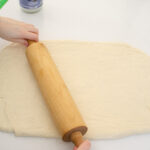 Rolling the dough for these easy cinnamon rolls into a large rectangle.